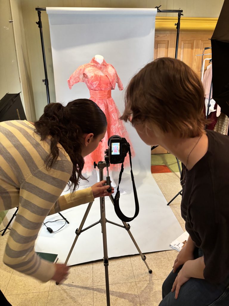 Two people photograph and pink dress on a mannequin.